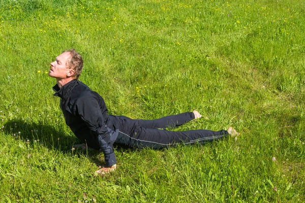 Mężczyzna wykonuje asany na trawie. — Zdjęcie stockowe