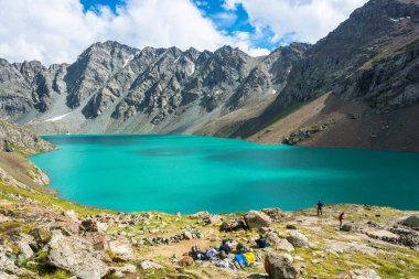 Bir dağ gölü Ala-Kul, Kırgızistan sahilde turistler