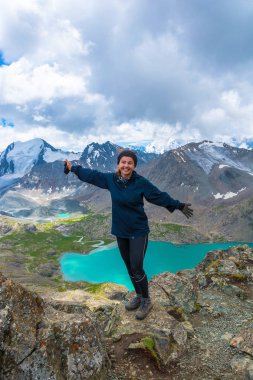 Kız bir dağ gölü bir arka plan üzerinde büyük bir kayanın üzerinde ayakta