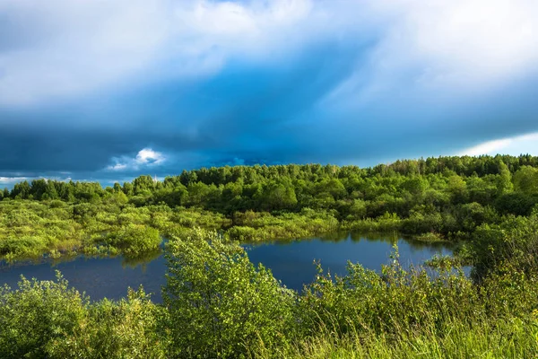 Paysage avec un petit lac et un ciel orageux . — Photo