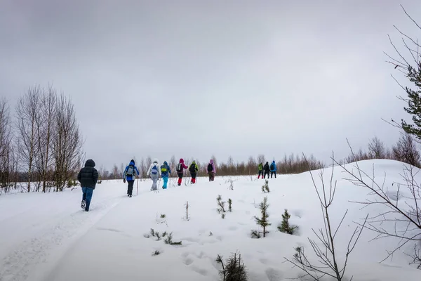 A small group of tourists climbing the gentle snow-covered slope — Stock Photo, Image