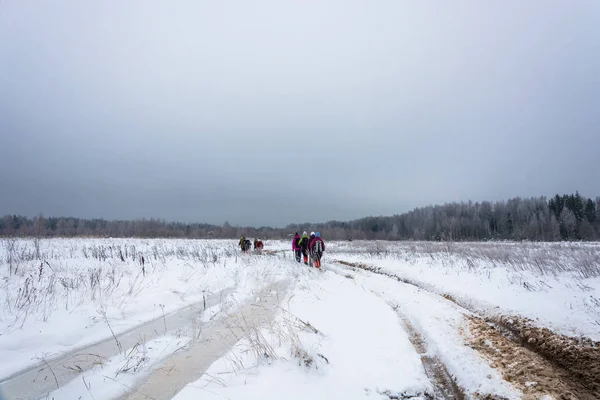 Un grupo de turistas caminando por el campo nevado . — Foto de Stock