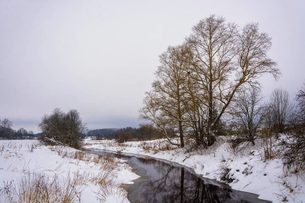 Une petite rivière sur les rives enneigées . — Photo