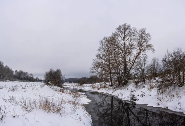 Une petite rivière sur les rives enneigées . — Photo