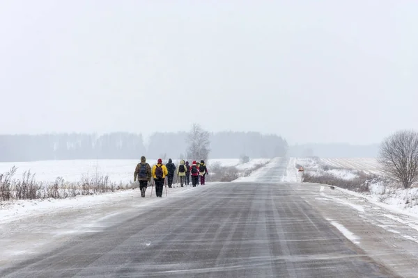 Un grupo de turistas caminando por la carretera en una ventisca . — Foto de Stock