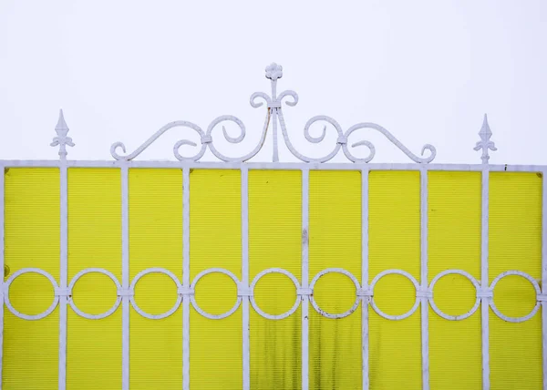 Cerca de metal branco em um fundo amarelo . — Fotografia de Stock