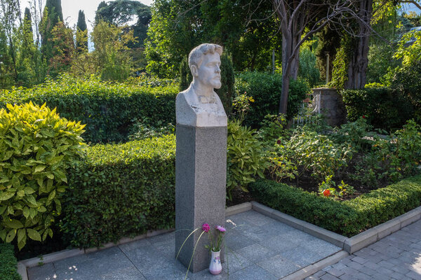 Bust of Russian writer Anton Pavlovich Chekhov in the courtyard of the summer cottage museum in Yalta on a summer day.