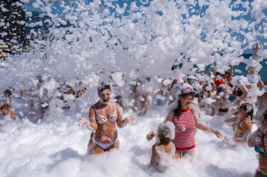 Kar beyazı köpük taneleri neşeli insanların üzerinde uyur. 