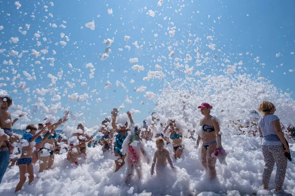 Fiocchi di schiuma bianca come la neve si addormentano su persone allegre sul — Foto Stock