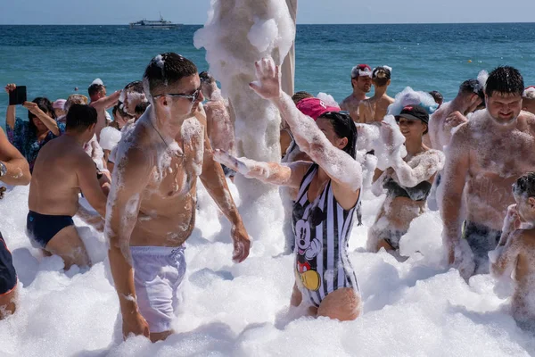 Veel vrolijke mensen op het strand in sneeuwwit schuim, 09 / 07 / 2019 — Stockfoto