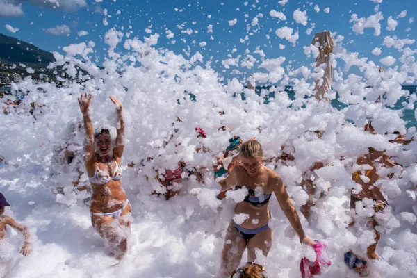 Copos de espuma blanca como la nieve se duermen en personas alegres en el —  Fotos de Stock