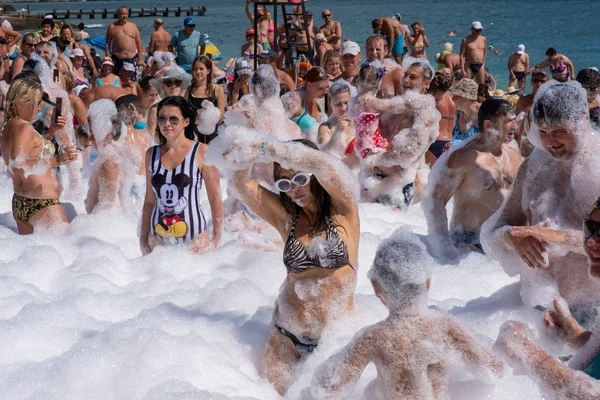 Molte persone allegre sulla spiaggia in schiuma bianca come la neve, 09 / 07 / 2019 — Foto Stock