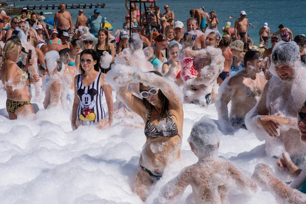 Veel vrolijke mensen op het strand in sneeuwwit schuim, 09 / 07 / 2019 — Stockfoto