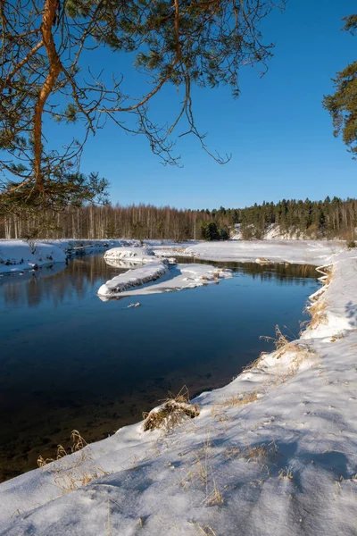 Tájkép egy kis folyóval a téli napsütésben és kék égbolton. — Stock Fotó