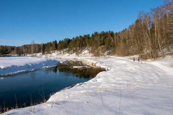Landskap med en liten flod och två skidåkare på en vinter solig da — Stockfoto