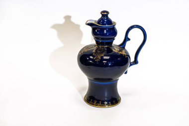 Beyaz arka planda altın desenli mavi seramik sürahi.. 