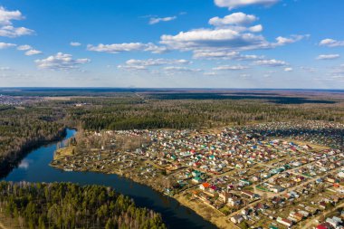 Güneşli bir bahar gününde Gorino köyünün ve Kharinka Nehri 'nin bir panoraması, insansız hava aracından çekilmiş bir fotoğraf.. 