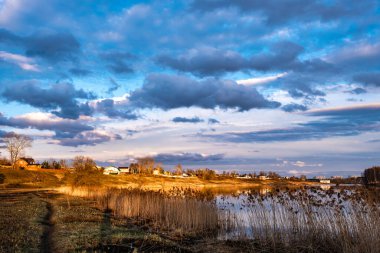 Uvod nehrinin kıyısında batan güneşin altın ışıklarında ve suda yansıyan güzel bulutlarda.. 