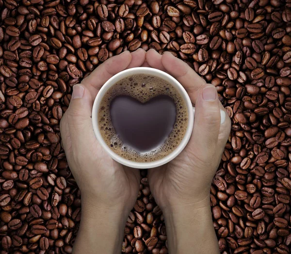 Amore tazza di caffè in mano con forma di cuore sul fagiolo — Foto Stock