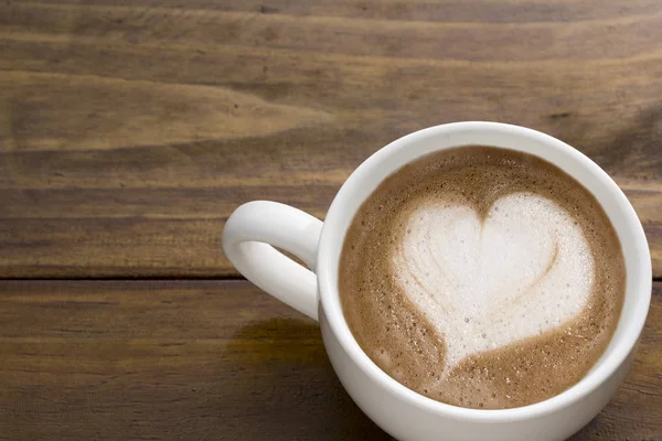 Кофе латте крем в форме сердца на верхней чашке кофе на рабочем столе — стоковое фото