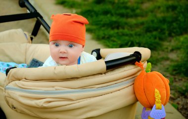 Balkabağı ve turuncu şapkalı şirin bir bebek portresi. Şaşkın bakışlı bir çocuk. Bebek arabasındaki bebek. Kocaman gözleri olan ufak tefek..