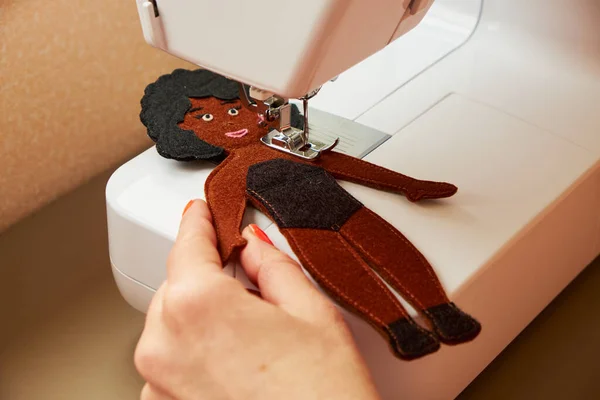 Handmade sewing toy dark-skinned girl. Felt doll with black hair. Mom\'s workplace.