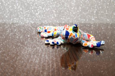 Cam bir masada renkli bir kertenkele. Refleks desenli cam masa. Renkli seramik model semenderi.