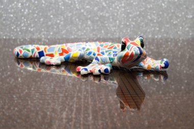 Cam bir masada renkli bir kertenkele. Refleks desenli cam masa. Renkli seramik model semenderi.