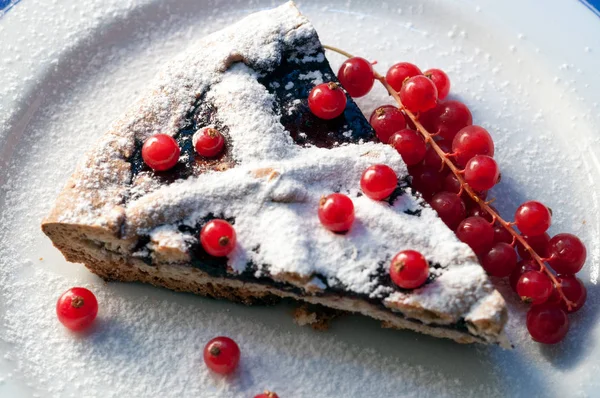 Süslü bir tabakta siyah ve kırmızı meyveli el yapımı turta ve krema şekeri.