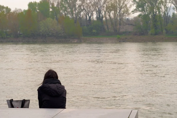BRATISLAVA, Slovakya - 09 Nisan 2019 - tek başına oturan kız nehre bakıyor