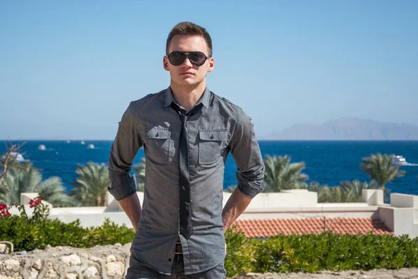 Homem de óculos de sol e uma camisa perto do mar — Fotografia de Stock