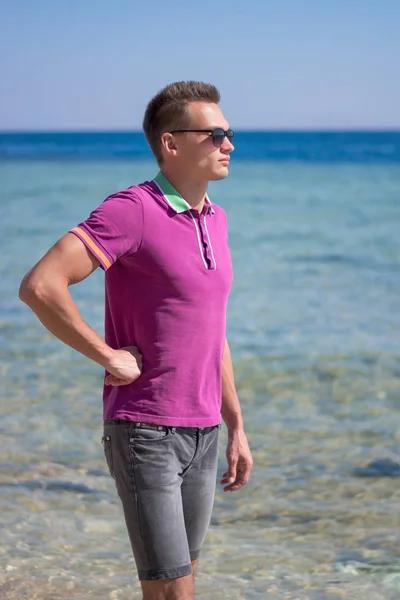 Hombre con gafas de sol camina por la orilla del mar — Foto de Stock