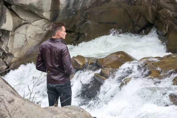 Young man standing near the waterfall — Stock Photo, Image