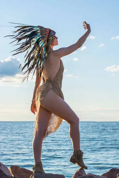 Egy amerikai indián stílust öltözött fiatal nő úgy néz ki magát a m — Stock Fotó