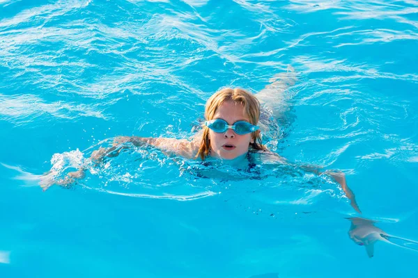 Meisje zwemt in het zwembad met glazen voor zwemmen — Stockfoto