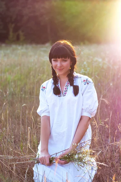 Una joven con una larga camisa bordada blanca recoge flores —  Fotos de Stock