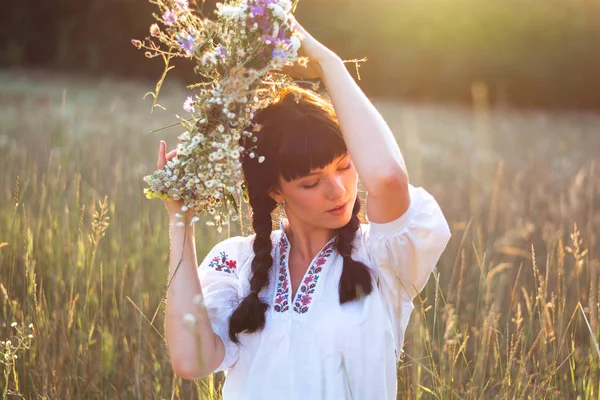 Une jeune femme dans une longue chemise blanche brodée met une couronne — Photo