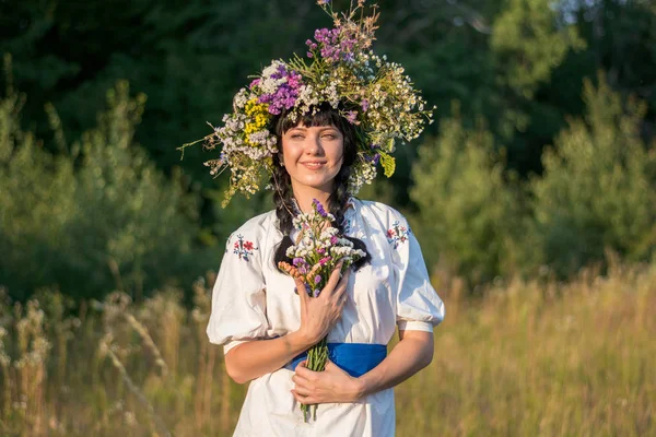 Une jeune femme dans une longue chemise blanche brodée et dans une couronne — Photo