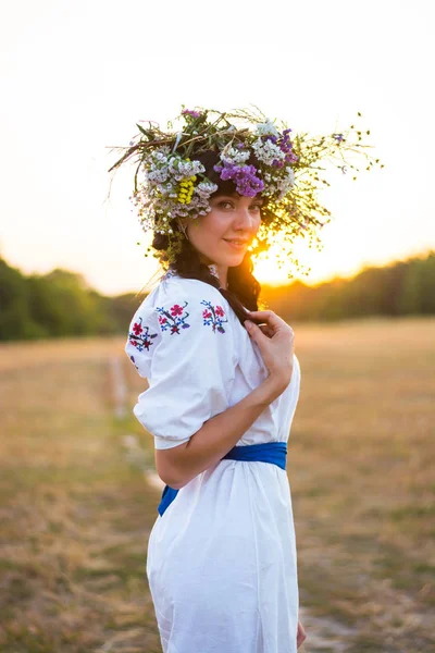 Uma jovem mulher em uma camisa bordada branca longa e em uma grinalda — Fotografia de Stock