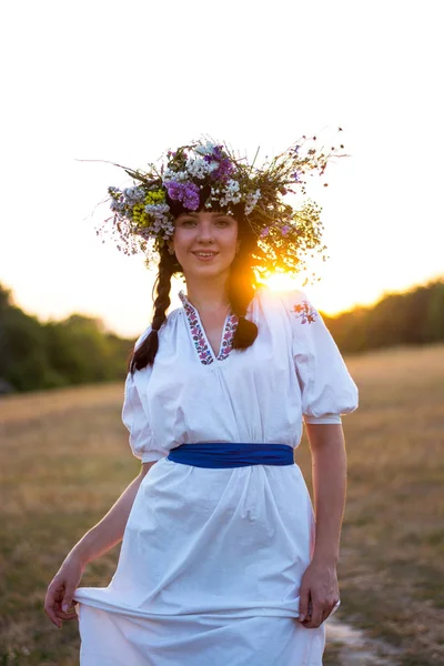 Uma jovem mulher em uma camisa bordada branca longa e em uma grinalda — Fotografia de Stock