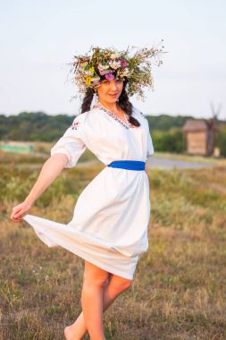 Genç bir kadın uzun beyaz işlemeli tişört ve çelenk 