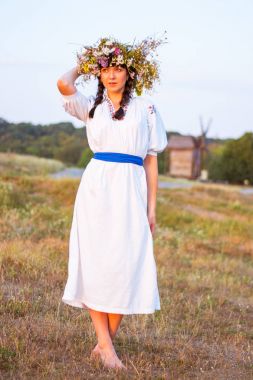 Genç bir kadın uzun beyaz işlemeli tişört ve çelenk 