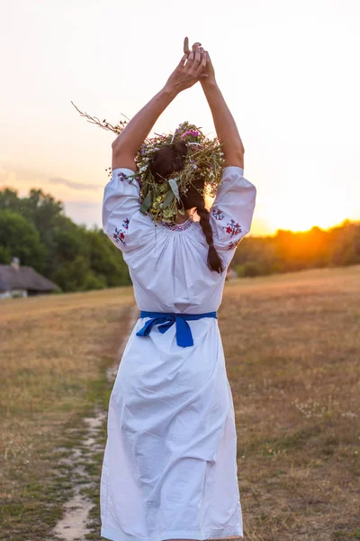 Een jonge vrouw in een lang wit geborduurd overhemd en een krans — Stockfoto