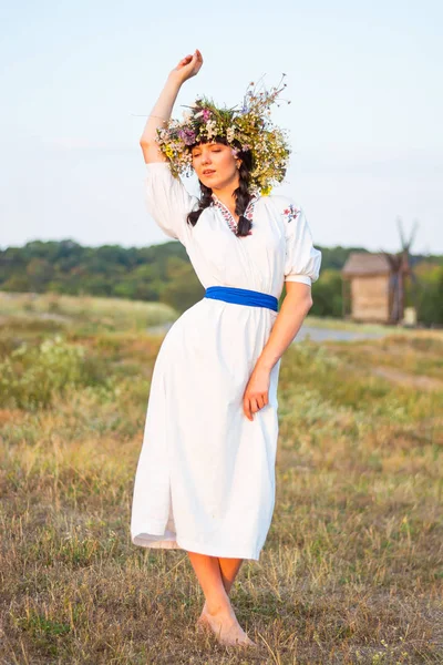 Una joven con una larga camisa bordada blanca y una corona de flores —  Fotos de Stock