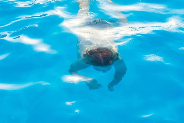 Meisje duiken en zwemt onder het water in het zwembad met glazen fo — Stockfoto
