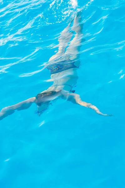 Meisje duiken en zwemt onder het water in het zwembad met glazen fo — Stockfoto