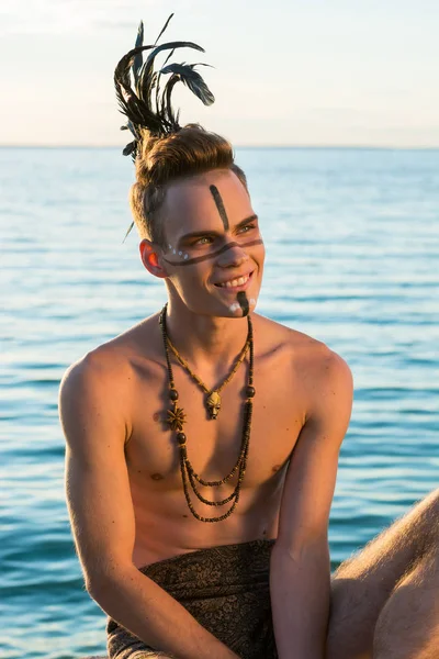 Man with an american indian coloring and feathers on his head is — Stock Photo, Image