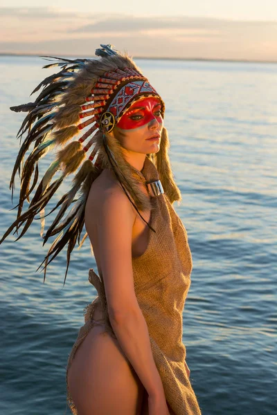 Женщина в американском индийском стиле стоит на берегу моря — стоковое фото