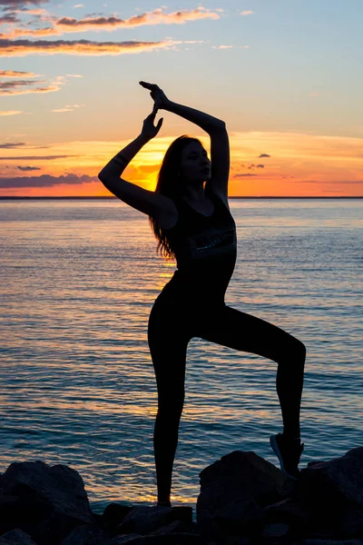 Silueta de una mujer esbelta, que hace yoga frente a la —  Fotos de Stock