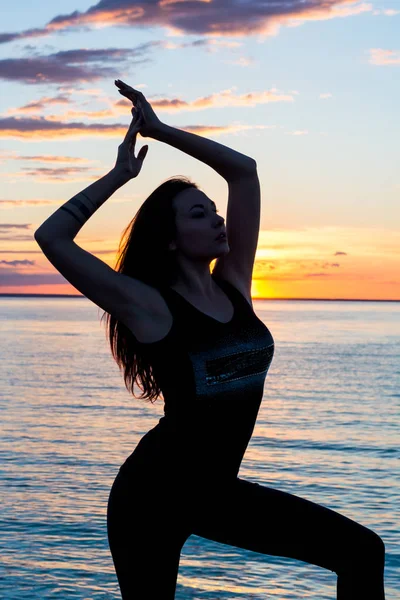 Silueta de una mujer esbelta, que hace yoga frente a la —  Fotos de Stock